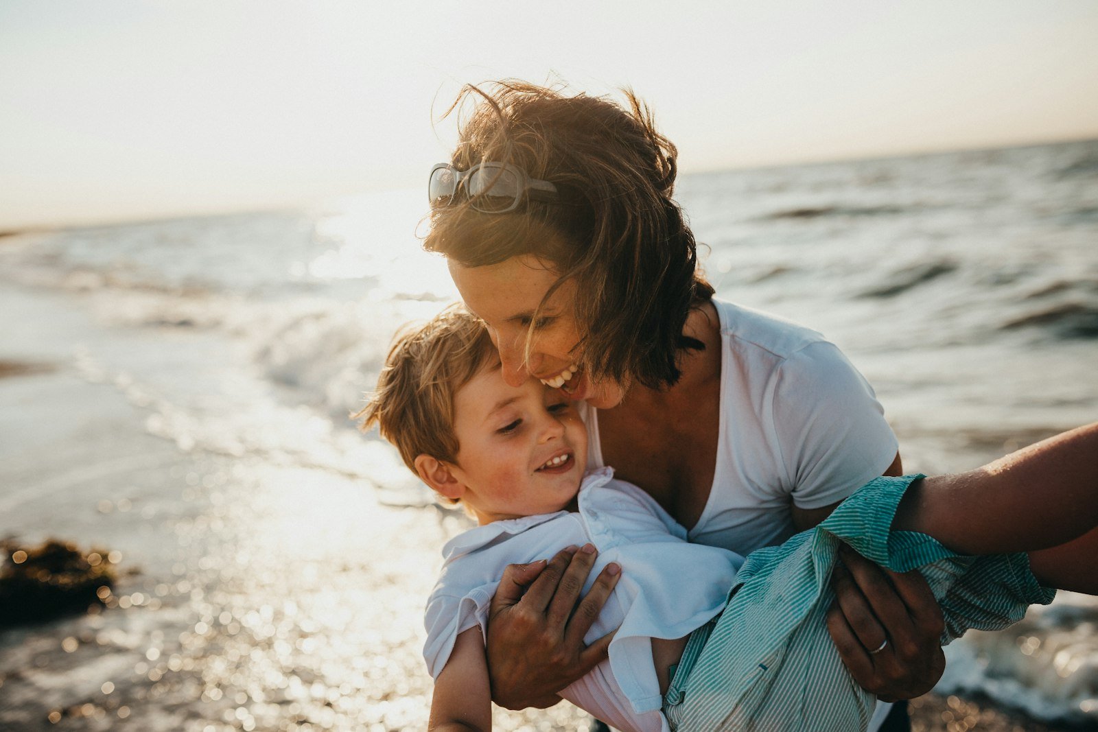 A parent and child sharing a joyful moment by the sea